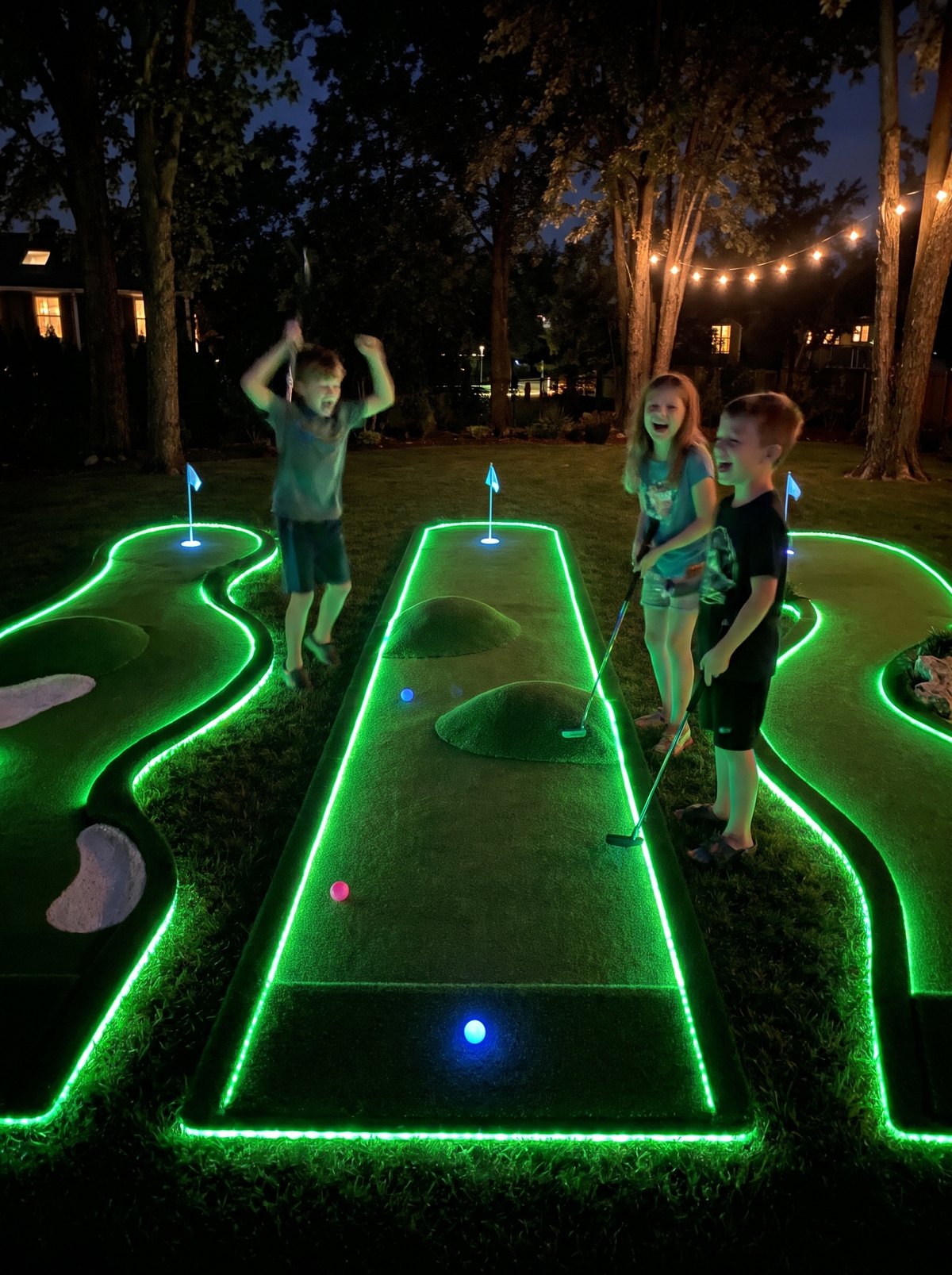 Kids laughing while playing Glow Putt at night with the greens glowing